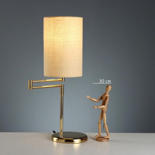 1980s-style table lamp with a swivel arm for directional and customizable lighting. The brass-plated metal frame lends a...