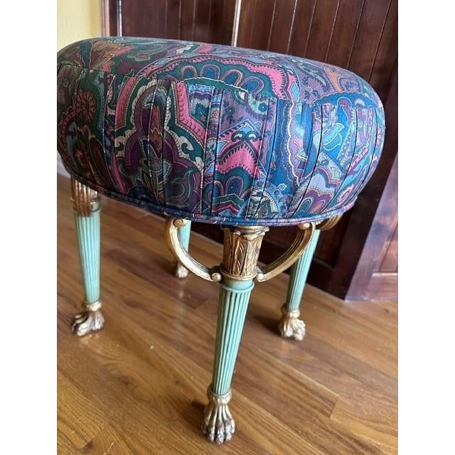 This elegant vanity stool features a plush, pleated seat upholstered in a vibrant, multi-color paisley fabric. The piece...