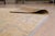 A 6' x 9' hand-knotted wool rug with a gold field with a faded gray-blue vine pattern and a soft, vintage-look finish....