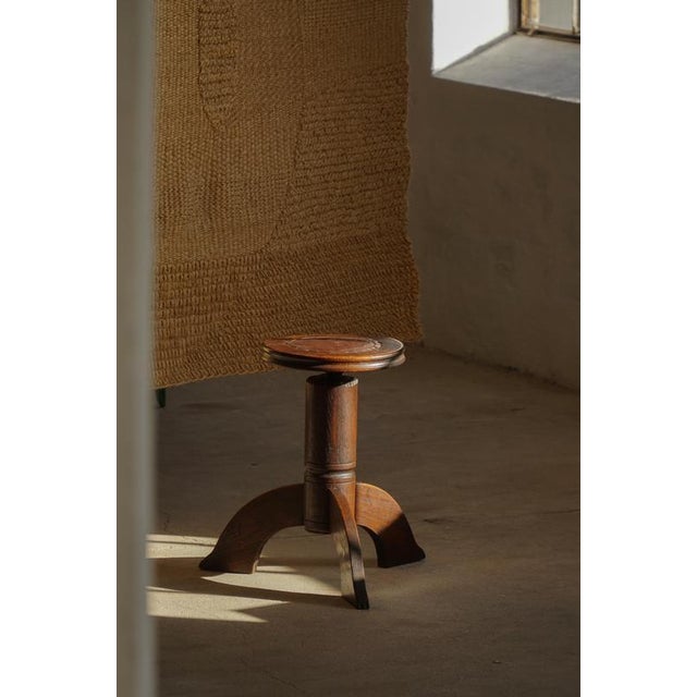 An early 20th century adjustable piano stool crafted in solid wood, reflecting the organic lines and decorative...