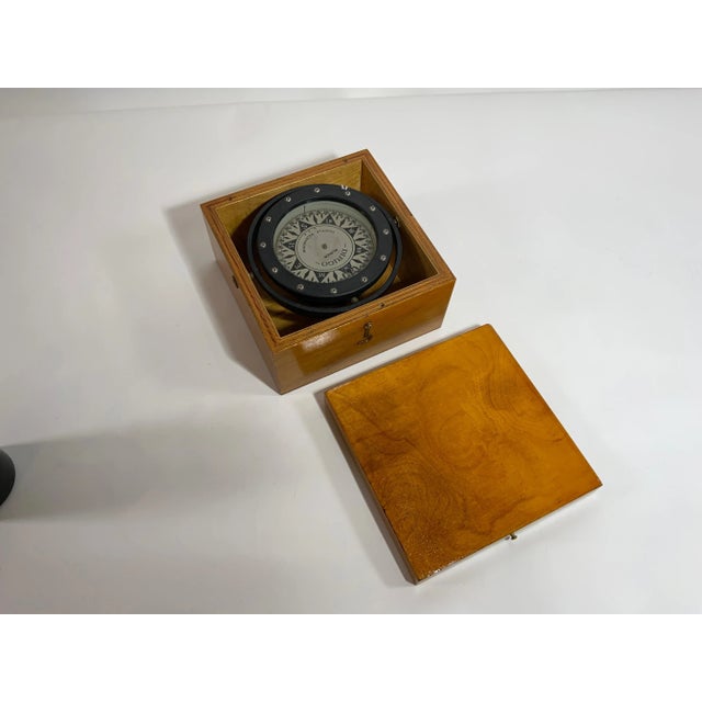 Gimballed brass boat compass by "Dirigo" of Seattle, Washington. With fleur-de-lis pointing north. Fitted to a birch box...
