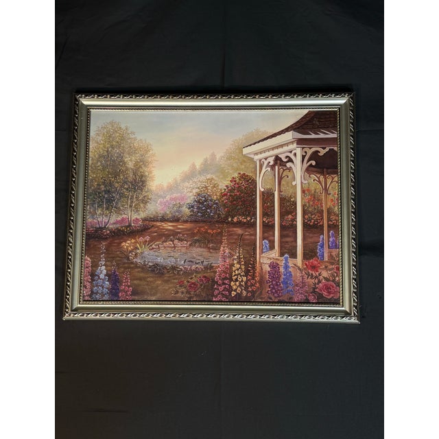 Beautiful framed garden landscape artwork featuring a gazebo, flowers, pond, trees, and warm sunset lighting. The scene...
