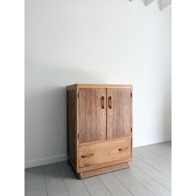A 1930s limed oak tall boy with wonderful yet simple detailing including curved profiles and a ribbed plinth base. This...