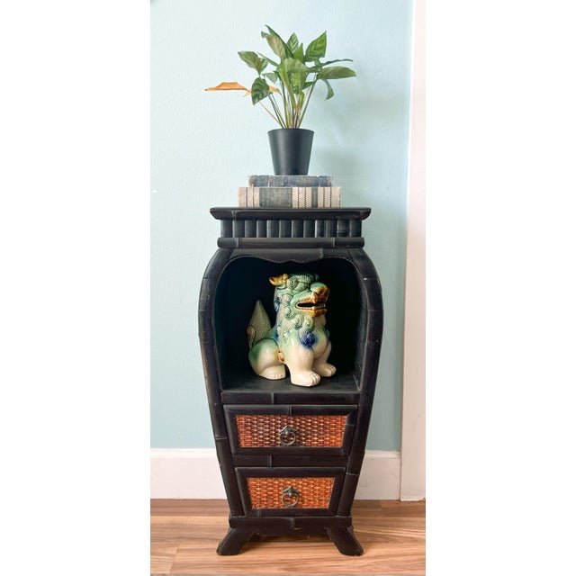 Vintage bamboo and woven rattan cabinet featuring a dramatic ebonized finish, gently bowed silhouette, and an open display...