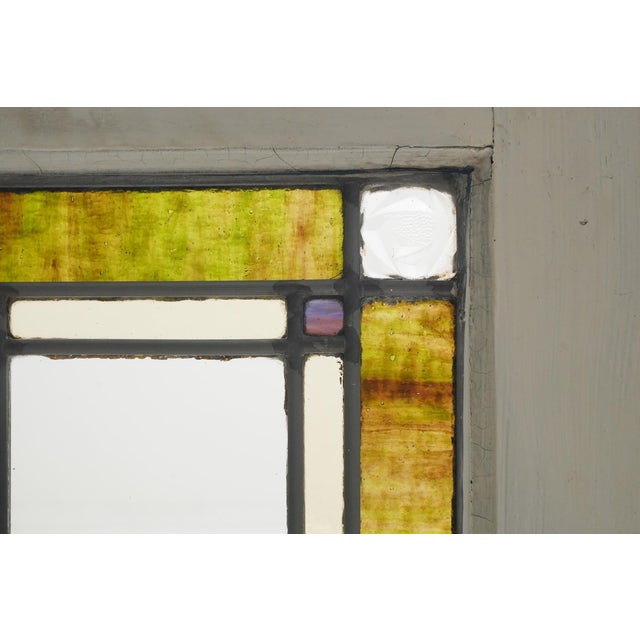 Antique Arts & Crafts style stained glass window featuring a classic symmetrical geometric design. The frame is made of...