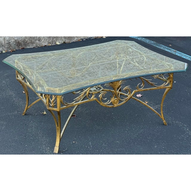 Gorgeous Hollywood regency style coffee table with intricate scrollwork metal base finished in rustic gold / brass and a...