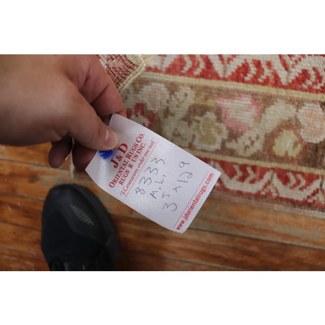 Early 20th century melon red field Turkish Ghiordes runner with an enchanting floral motif Measures: 3'5” x 12'9”.