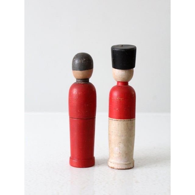 This is a pair of mid 20th century figural boxes. A solider and a woman in a red dress shape the tall slender boxes. They...