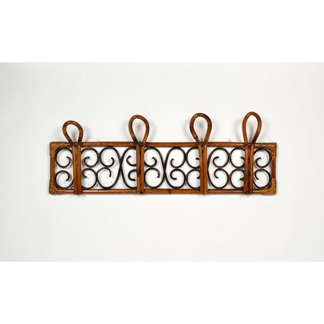 Midcentury coat rack stand in bamboo and rattan with four hooks. Made in Italy in the 1960s. The rattan material provides...