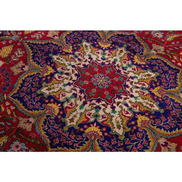 Beautiful vintage Persian Tabriz hand-knotted wool rug with a red field. This piece has a navy blue frame and multicolor...