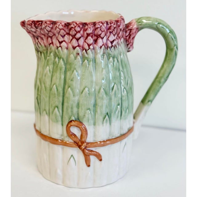 Vintage Majolica style pitcher with asparagus spear motif. Burgundy heads on green stalks all tied up with a brown bow....