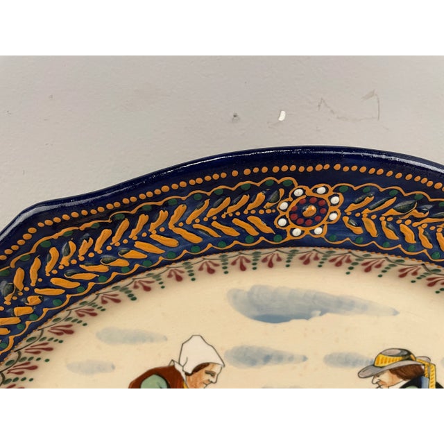 A platter from the Factory of HB Quimper with the broderie border with in the center a woman and a man sitting. A good...