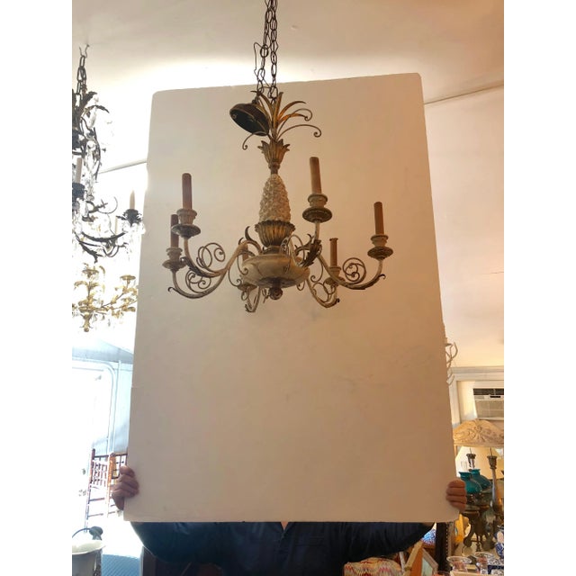 A classically elegant off-white and gold pineapple motif Italian chandelier of carved wood, iron and tole having 6 arms...