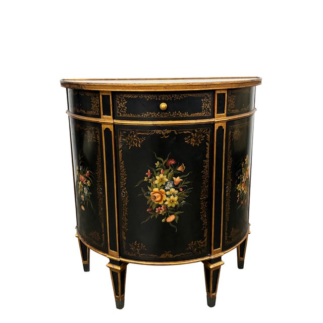 Elegant Theodore Alexander Louis XVI-style demilune cabinet featuring a dramatic black finish, rich gilt detailing, and...