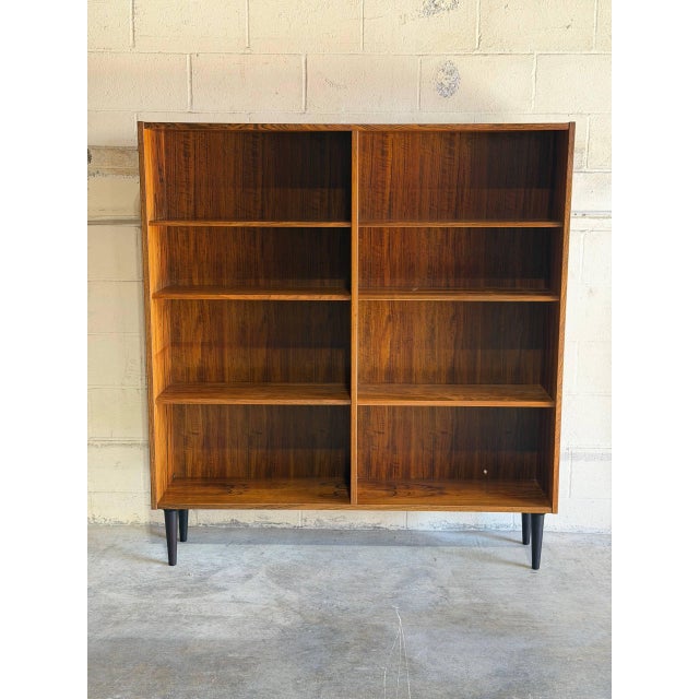 Dual open bays with adjustable shelves create a striking architectural silhouette. Tapered legs elevate the cabinet to...