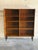 Dual open bays with adjustable shelves create a striking architectural silhouette. Tapered legs elevate the cabinet to...