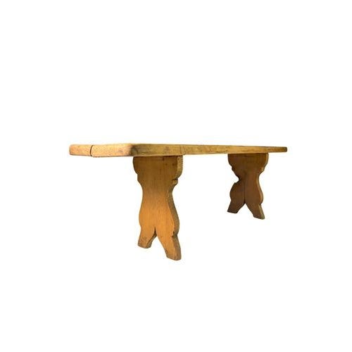 Rustic wooden stool featuring shaped legs, it can be considered as a bench given the length of the seat.