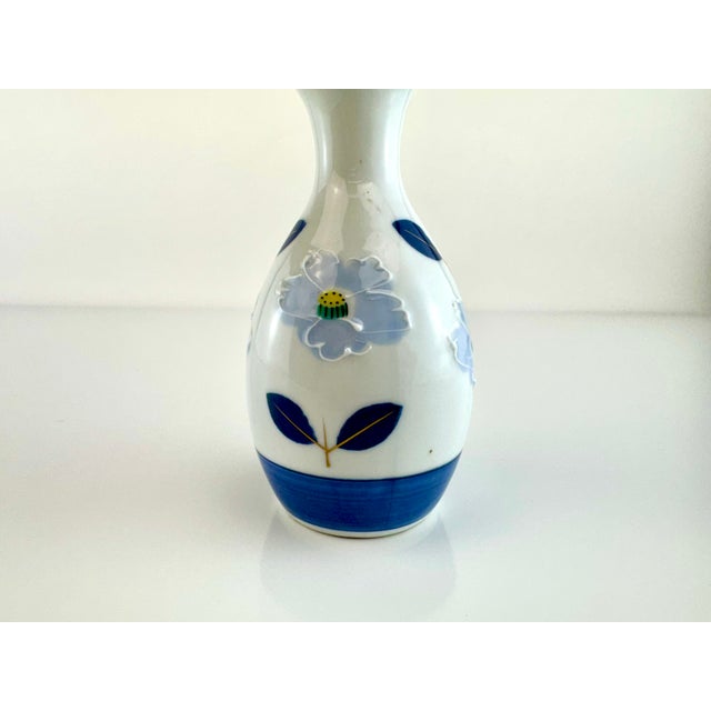 This vintage Japanese porcelain sake bottle features a graceful bulbous form and a delicately flared rim, adorned with...