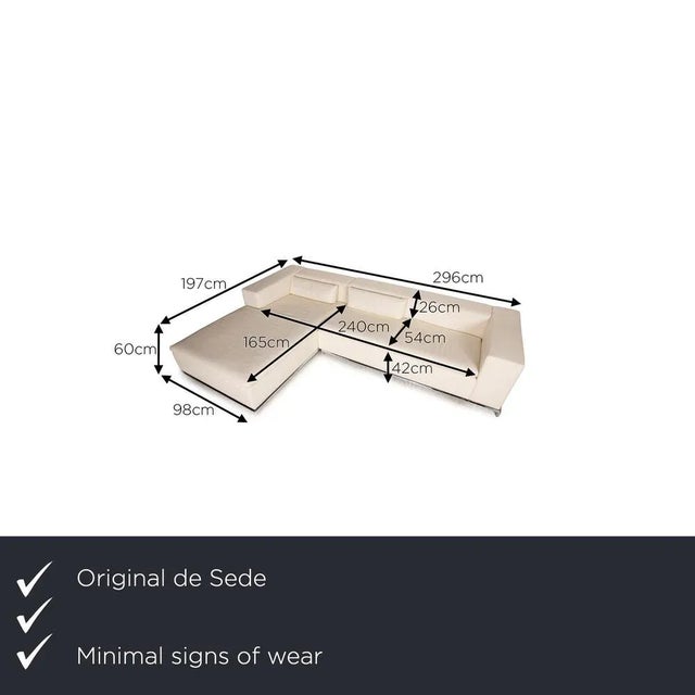 The corner sofa DS 7 of De Sede is covered with a cream-colored real leather and stands on narrow metal feet. It is...