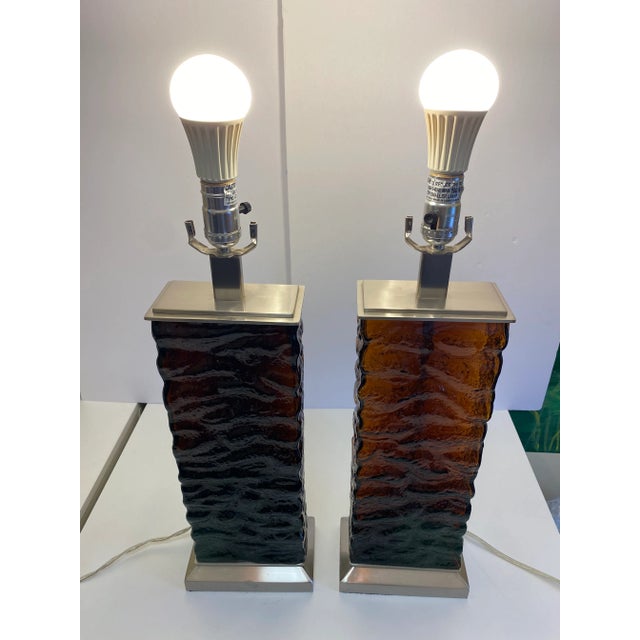 A dramatic pair of amber glass table lamps that bring warmth, texture, and architectural presence to a room. Rectangular...