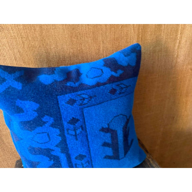 A stepped vessel-like emblem rises in dark navy on the right side of the piece, framed by a narrow botanical guard stripe...