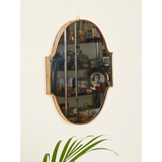 Wonderful and unique small shield-shaped mirror with a solid brass frame. This elegant piece was produced in Italy during...