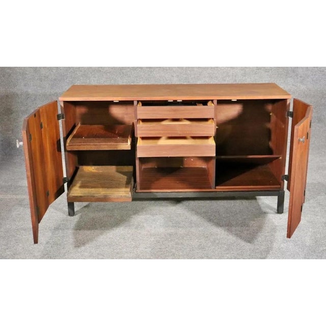 Mid-century modern sideboard with bi-fold doors, matte black base, and matching black exposed hinges. Designed for...