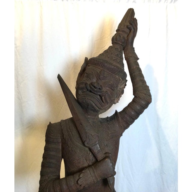 A hand carved hardwood sculpture of a Balinese warrior circa 1900. The sculpture with expressive face, holding sward in...