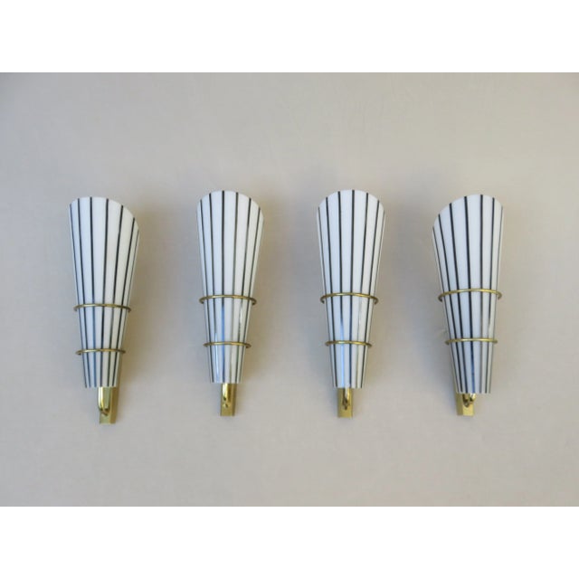 A set of 4 elegant wall lights from the 50s from Italy. The wall mounts are made of brass. The lampshades are in the form...