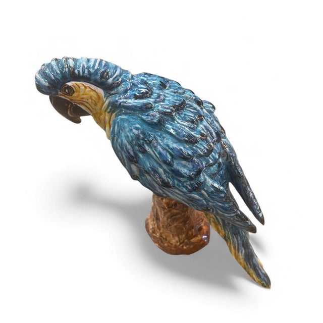 This vintage Maiolica-style ceramic sculpture depicts a Blue and Gold Macaw perched on a tree stump, finished in a rich,...