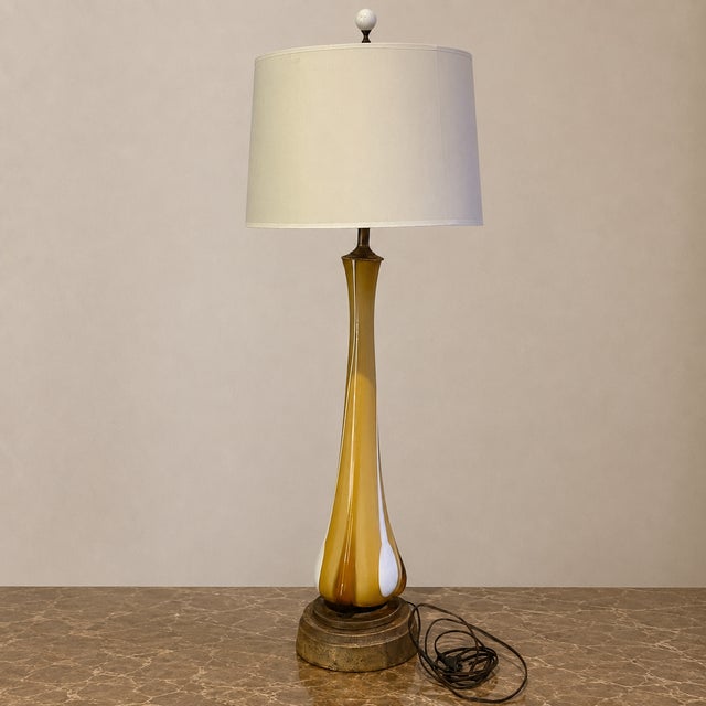 This beautiful mid-century vintage handblown glass table lamp features a tall, sculptural silhouette with amber, honey,...