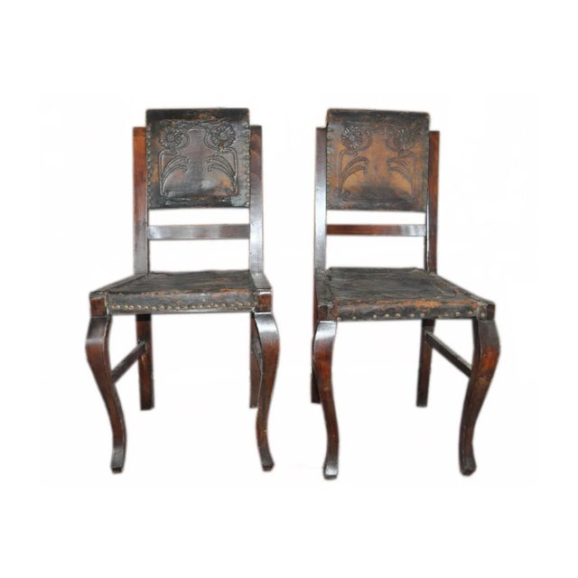 - Set of two Hungarian dining chairs - Retains its original embossed brown leather upholstery - Comes with a sturdy wooden...