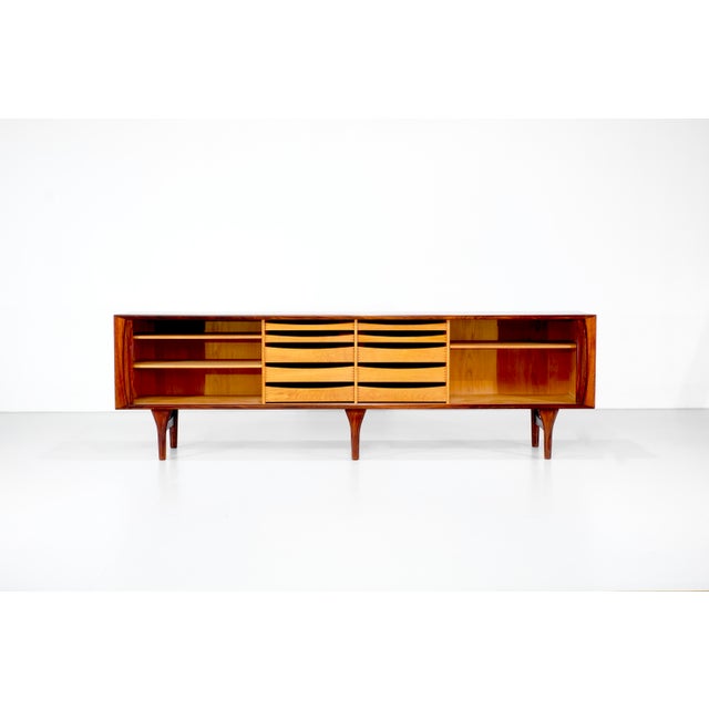 Large wooden sideboard with two sliding doors, comprising four compartments: two with shelves and two with drawers....