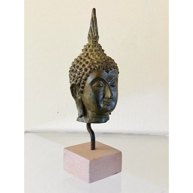 A bronze head of a Buddha custom mounted on a sandstone base. In the classic Thai style.