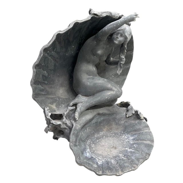 This vintage cast lead decorative sculpture features an Art Nouveau-inspired nymph seated gracefully within a large open...