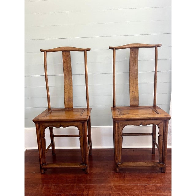 A pair of Chinese lamphanger walnut dining chairs. The matching pair features an arched crest rail and a serpentine back...