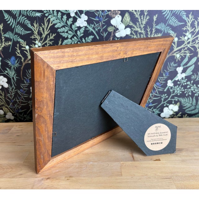 Capture the essence of fall with this watercolor landscape, featuring a peaceful lake surrounded by puffy cattails and...