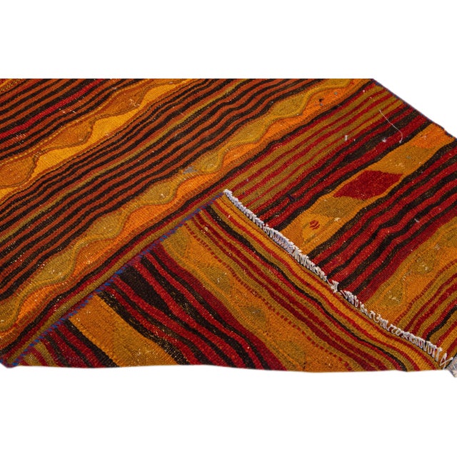 Beautiful vintage Turkish Kilim hand-knotted wool runner with an orange field. This rug has multicolor accents in an all-...
