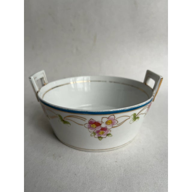 A single round porcelain bowl with square handles and floral decoration. Could be used for pet food or as a catch all bowl.