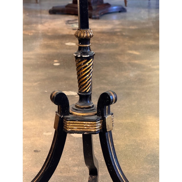 A striking Regency candlestand in ebonized and gilt wood, with a shaped rectangular top decorated in chinoiserie — the...