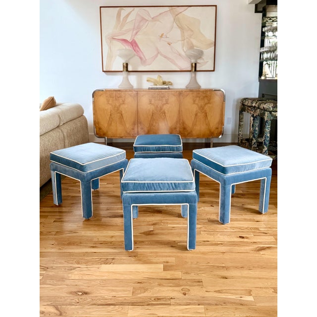 Classic Parsons-style ottomans reupholstered in a powder blue cotton velvet with cream contrast piping. Sold by the pair.
