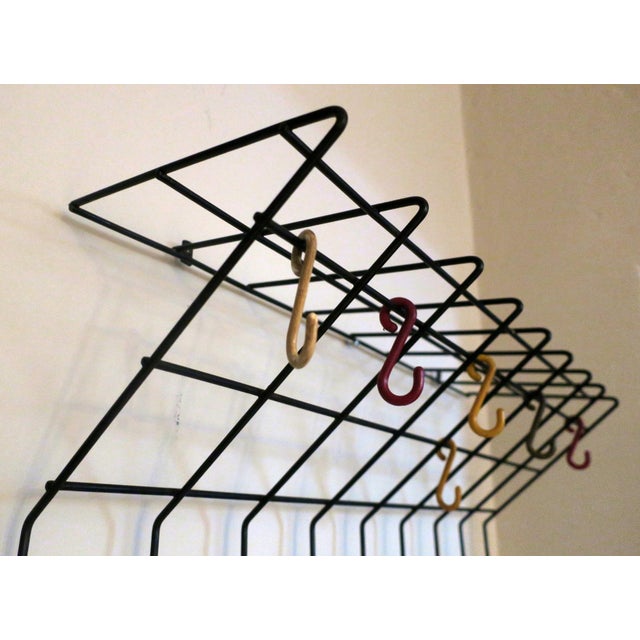 String' wall mounted coat, hat and umbrella rack in metal with multi-coloured hooks and umbrella holders at the base,...