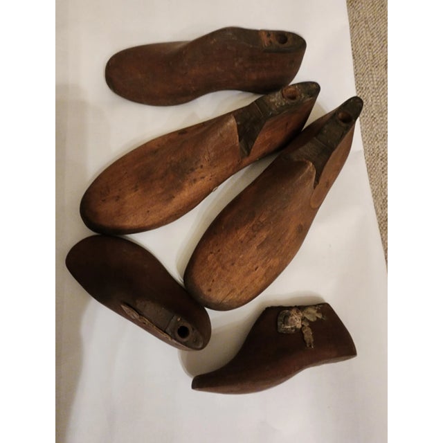 Collection of five vintage wood and metal shoe molds. Two smaller child shoe molds have milagros added to them.