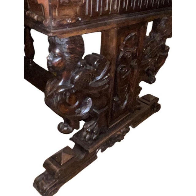 A powerful and architecturally striking Renaissance Revival carved walnut trestle table, dating to the late 19th century...