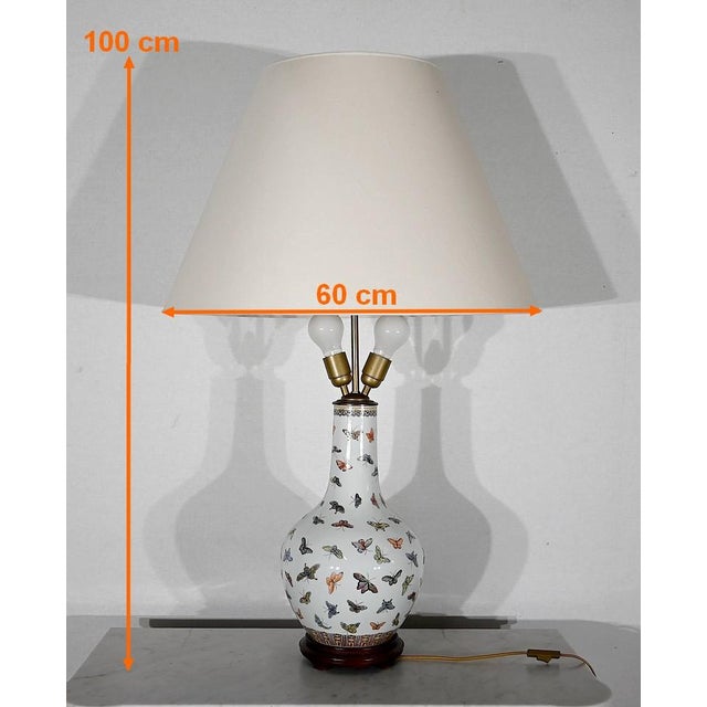 Large lamp formed by a pansu vase on a white background, decorated with multicolored butterflies, placed on a ground...