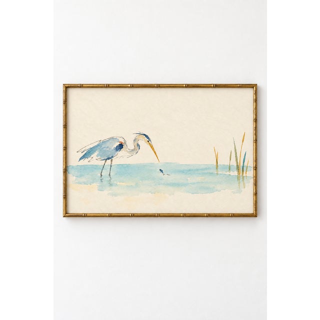 A blue heron leans toward a tiny fish in shallow turquoise water in this serene coastal bird art print. Delicate sketch-...