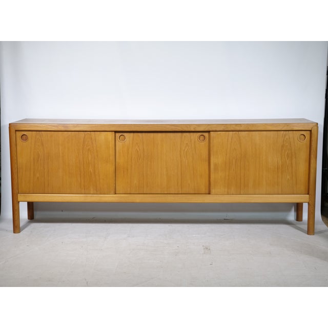 Danish Design teak sideboard by Bramin, 1960s. Long cabinet with three sliding doors, round recessed handles, and a...