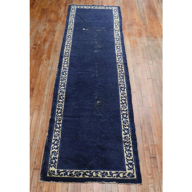 An early 20th Century Rare Chinese runner with a patternless navy field and floral ivory border. Professionally Cleaned...