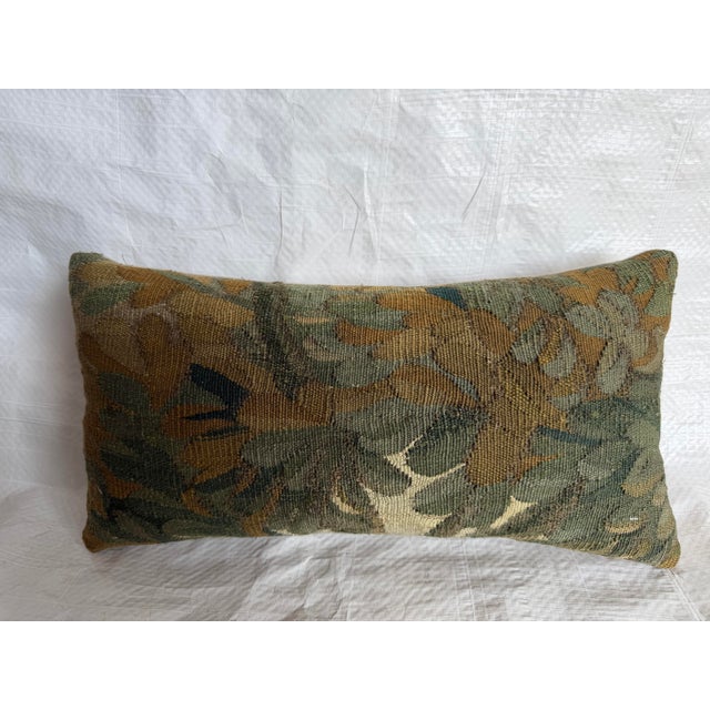 A refined 17th century Flemish tapestry pillow, composed from an antique verdure tapestry fragment depicting a stylized...