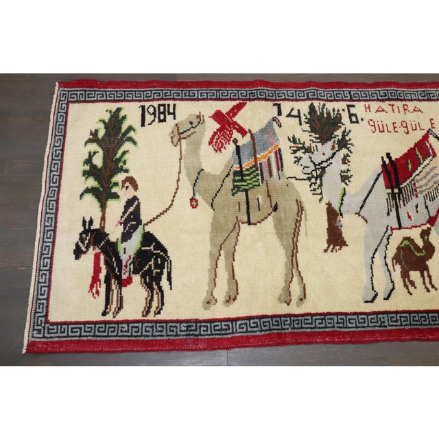 A turkish pictorial small rug with a camels being carried by a caravan . dated 1984 and looks to be a dowry gift based on...